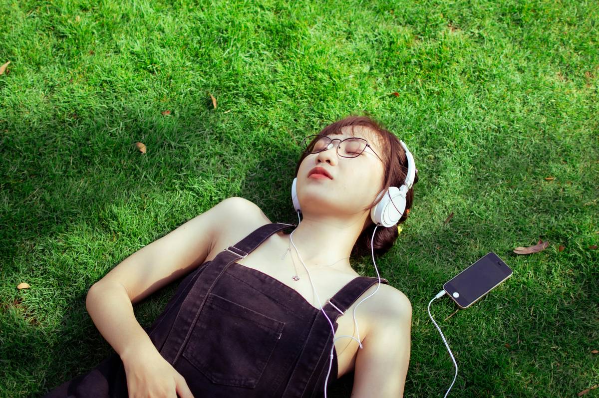 Person meditating with headphones while listening to what is therapeutic music, surrounded by calming nature visuals