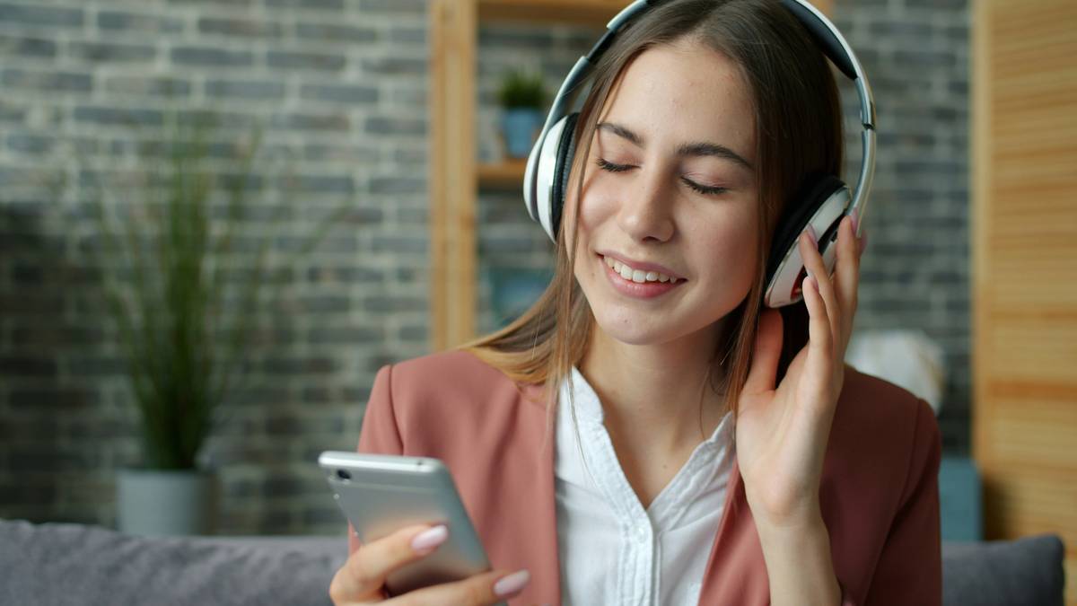 Person meditating with headphones while listening to music therapeutic benefits-focused playlist