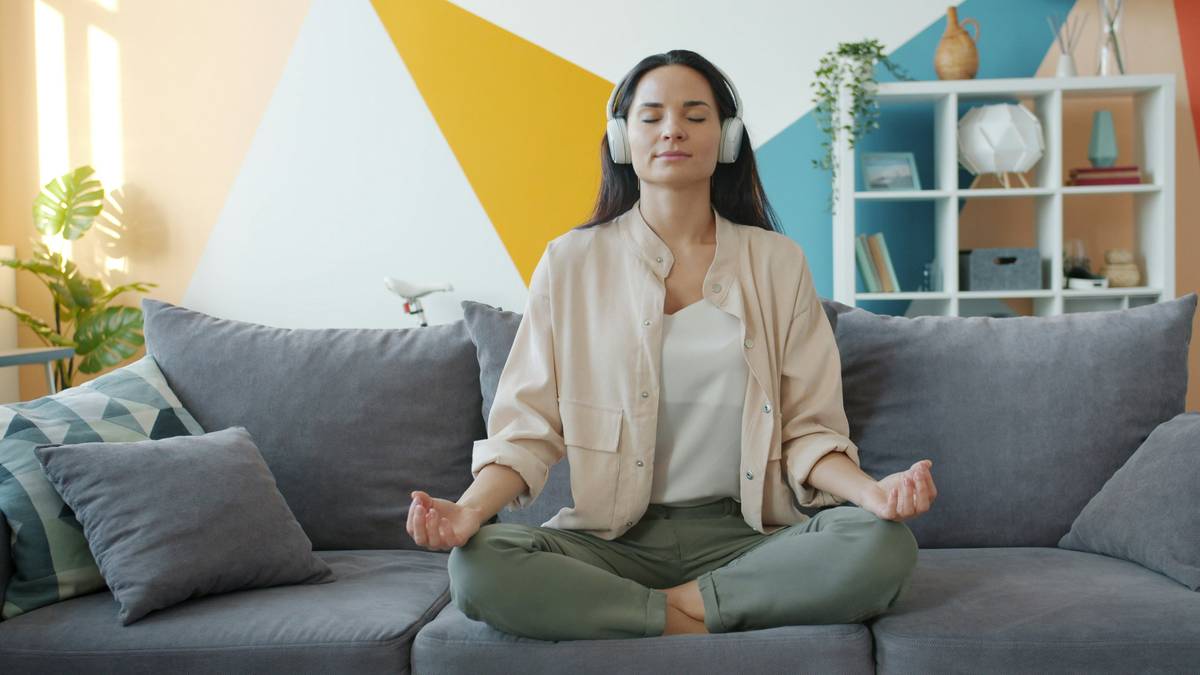 Woman practicing music therapy playlist activity with headphones and journal in a quiet room