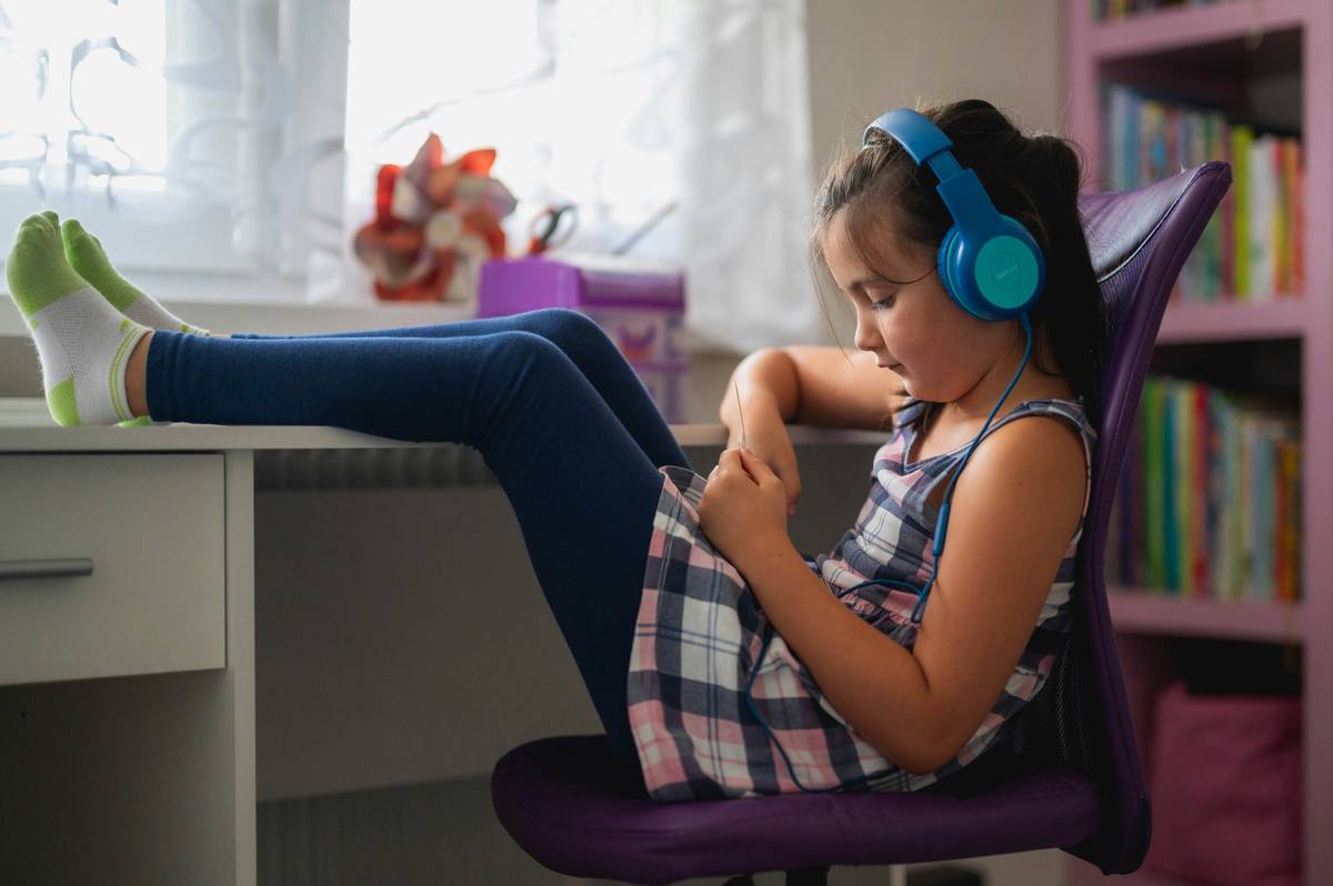 mindfulness meditation music for kids playing on a tablet while a child sits cross-legged on a rug with eyes closed